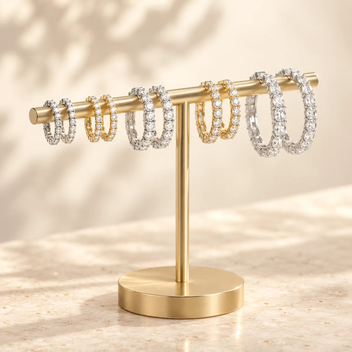 Diamond hoop earrings in white and yellow gold on a gold display stand