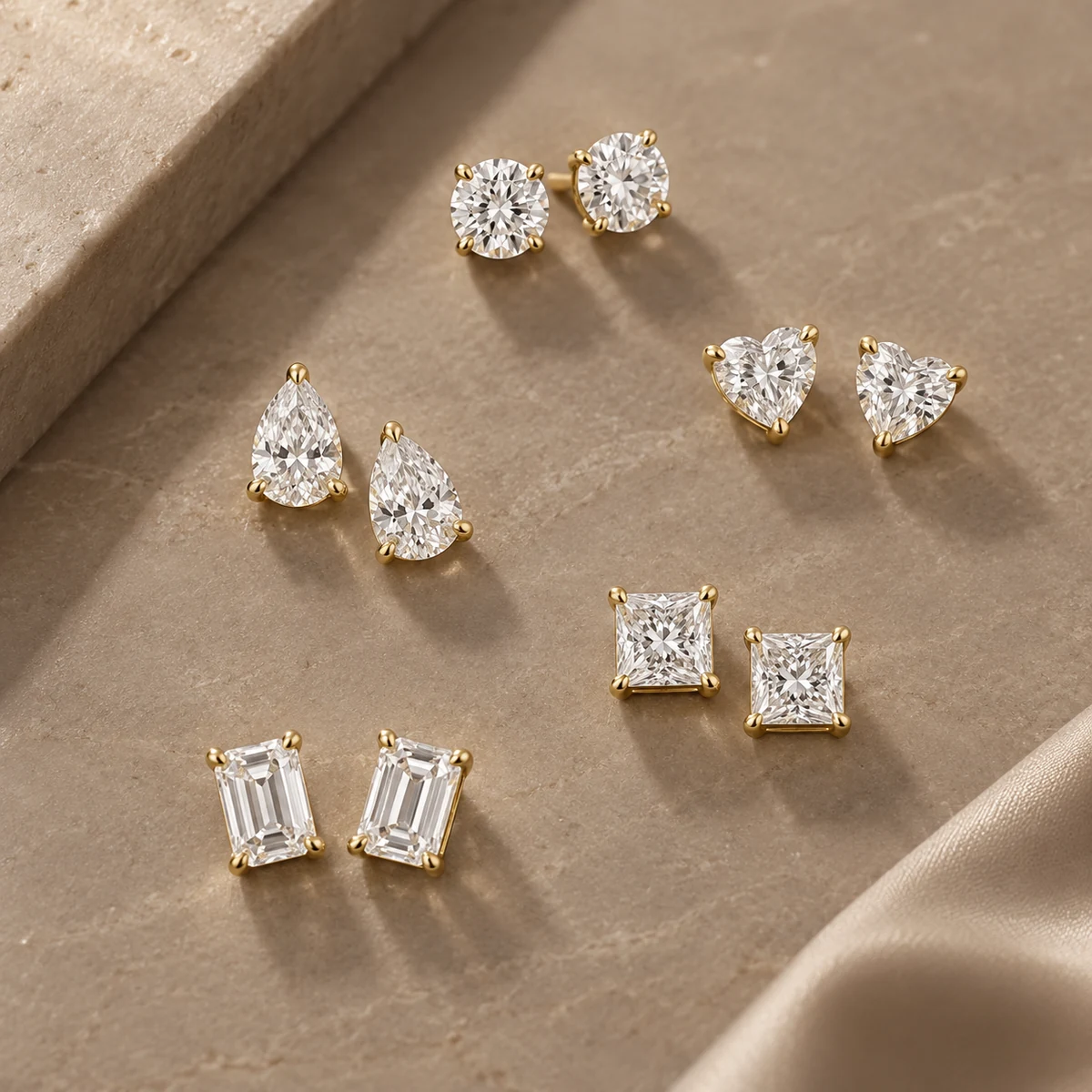 Diamond stud earrings in round, pear, heart, princess and emerald cuts set in yellow gold