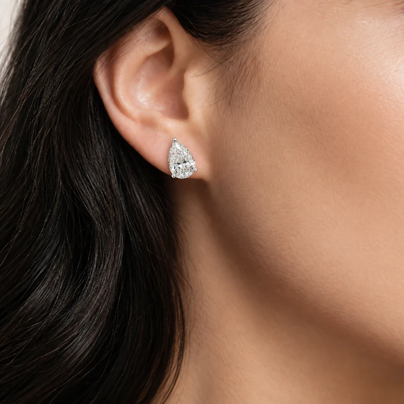 Woman wearing a pear shaped diamond solitaire stud earring in white gold